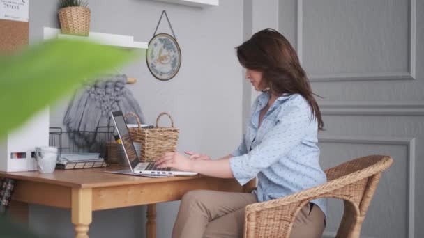 Mladá žena pracující doma na notebooku. dívka na pohodlném pracovišti — Stock video