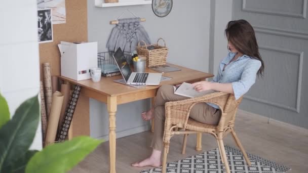 Freelancer reads magazine in home studio. girl designer works at home — Stock Video