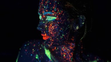 Kızların yüzünde neon boya. parlak boyalar ile boyanmış genç bir kadının portresi.