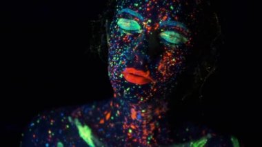 Ultraviyole ışıkta yakın çekim portre. koyu boya parıltı ile boyanmış yüz.