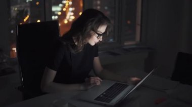 Gözlüklü akşam geç bir bilgisayarda çalışan bir iş kadını. iş yerinde genç uzman portresi