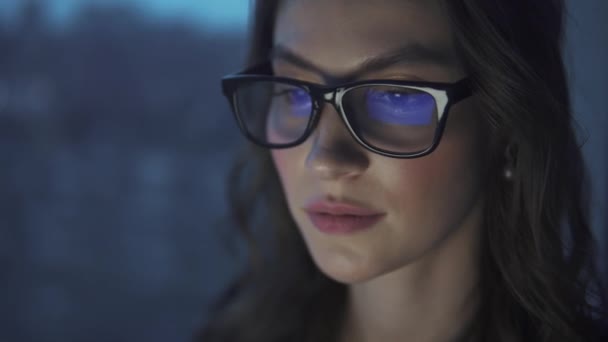 Отражение монитора в очках. привлекательная молодая девушка работает на ноутбуке — стоковое видео