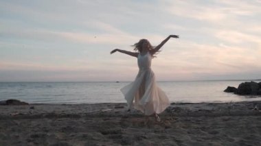 akan bir elbise gün batımında sahilde dans genç balerin.