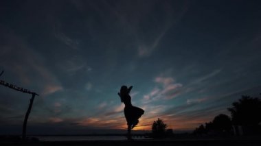 gün batımı gökyüzüne karşı bir balerin silueti. kız güzel tiptoes ayakta dans eder.