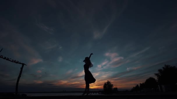 Silhueta de uma bailarina dançando na ponta dos pés contra o céu por do sol — Vídeo de Stock