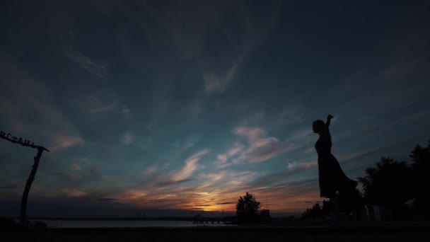 Baletka dělá nádherné skoky. silueta balleriny proti obloze slunce — Stock video