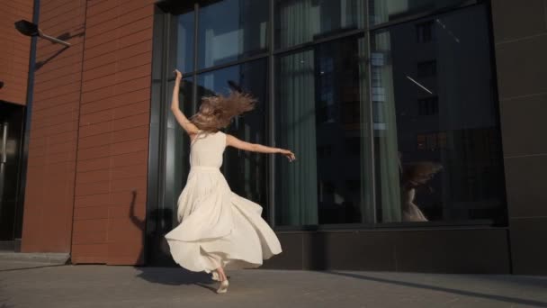 Κορίτσι με ένα τρεχούμενο φόρεμα που χορεύει στο δρόμο στην πόλη — Αρχείο Βίντεο