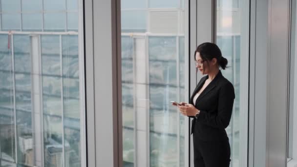 Moderne zakenvrouw met een smartphone in haar handen in de lobby van een modern Business Center — Stockvideo