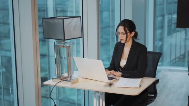 Portret van zakenvrouw die aan tafel werkt in een modern kantoor. zakenvrouw werkt op computer zittend bij het raam op kantoor — Stockvideo