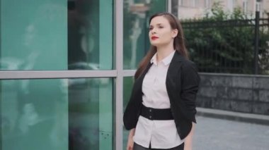 kendine güvenen bir iş kadının portresi. Genç bir kadın iş merkezinin yanında elinde bir evrak çantası ile yürür