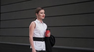 Kendine güvenen iş kadını bir fincan kahve ile sokakta yürürken. bir iş elbiseli Genç kadın bir toplantıya aceles.