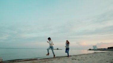çocuklar ılık bir sonbahar gününde denizin etrafında sıcak bir şekilde koşarlar.