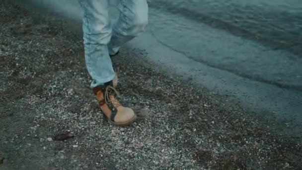 Barnpromenader längs stranden. en liten flicka i varma kläder tillbringar tid på stranden — Stockvideo