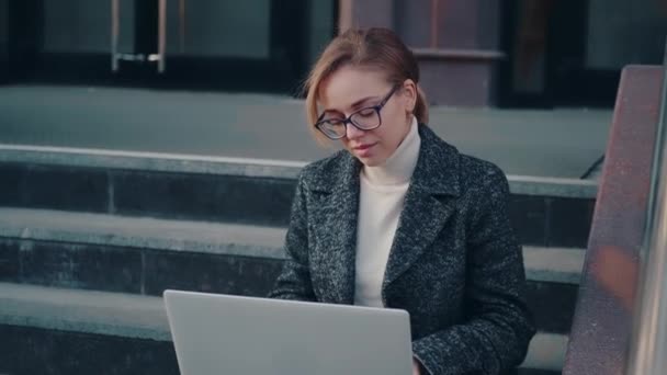 Студент використовує ноутбук, сидячи на відкритому повітрі . — стокове відео