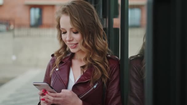 Bájos fiatal nő használ egy okostelefon és boldogan mosolyog, miután elolvasta az üzenetet — Stock videók