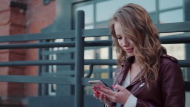 Elinde akıllı telefon olan sevimli bir kızın portresi. Genç bir kadın cep telefonu kullanıyor.