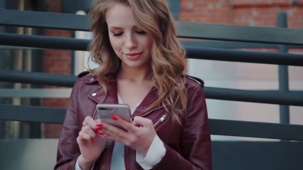 Portret modnej młodej kobiety z telefonem komórkowym w rękach. atrakcyjna dziewczyna na czacie na smartfonie — Wideo stockowe