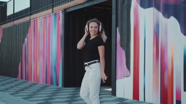 Portrait of an artistic girl dancing in headphones outdoors — Stock Video