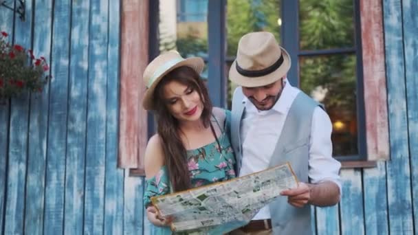 観光客のカップルは、旅行で地図を探索しています。若い女性と男が旅行で街を歩き回る — ストック動画