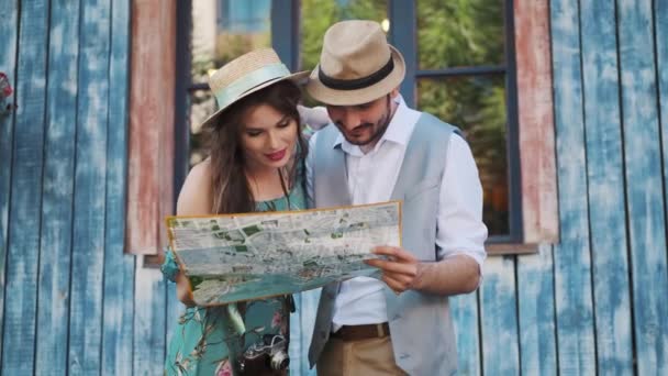 Turistas felizes viajando. um homem e uma mulher seguram um mapa da cidade — Vídeo de Stock