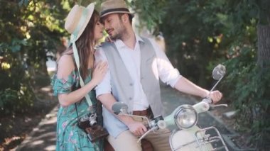 couple in love. young man and girl sitting on a scooter. gentle touches and kisses