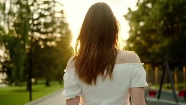 Attraente giovane donna si gira e guarda la fotocamera alla luce del sole — Video Stock