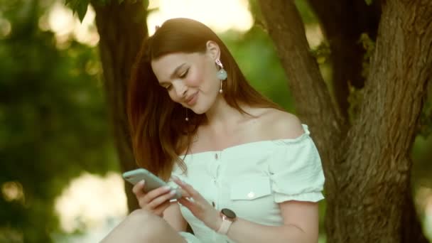 Jeune femme textos sur un téléphone mobile en plein air — Video