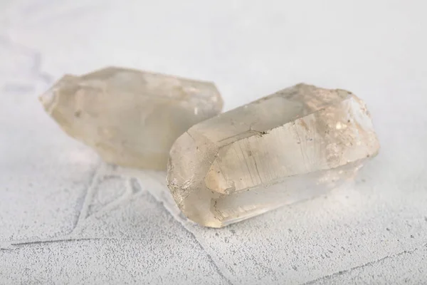 Natural mineral rock specimen - rock crystal of quartz gemstone from Subpolar Ural on white cement background.