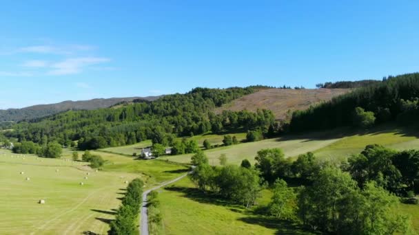 Vuelo sobre campos verdes y tierras de cultivo con fardos de heno en Escocia — Vídeo de stock