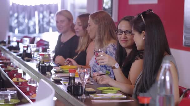 Группа девушек сидит в ресторане Sushi Bar и ест азиатскую еду — стоковое видео