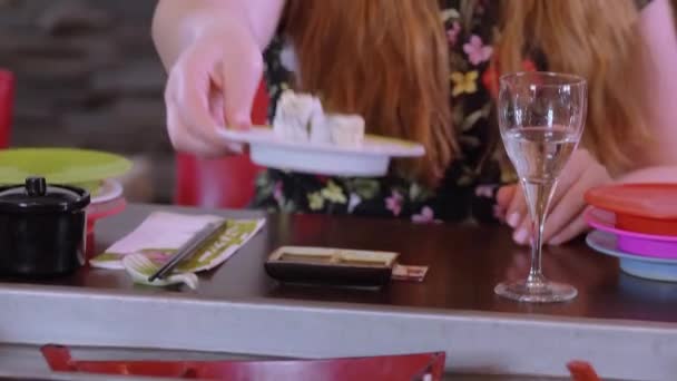 Menschen in einem laufenden Sushi-Restaurant genießen asiatisches Essen von der Bar — Stockvideo