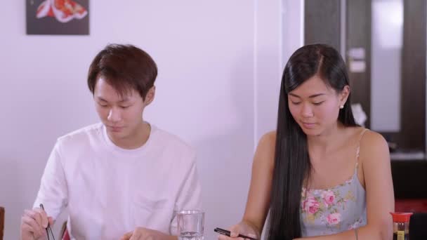 Joven pareja asiática en un restaurante de sushi - comiendo rollos de sushi recién hechos — Vídeos de Stock