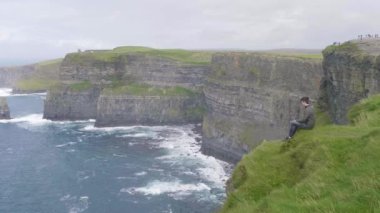 Adam İrlanda Moher kayalıklarla üstüne oturuyor