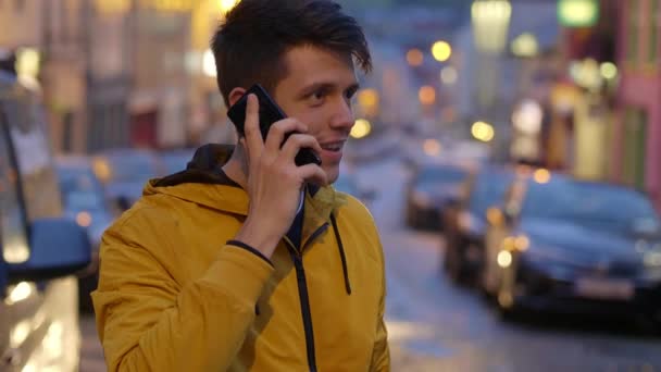 El tipo toma una llamada mientras está parado en medio de una calle — Vídeo de stock