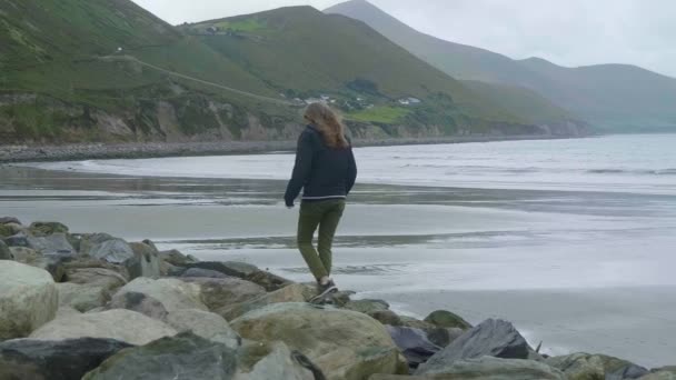 Girl climbs over the rocks of the Irish coast — Stock Video