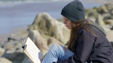 Kız liman bölgesinde otururken bir kitap okur