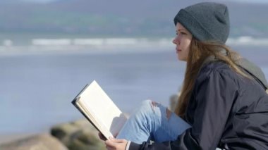 Genç kadın doğada kitap okurken rahatlatır