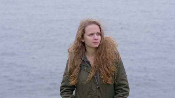 Joven chica reflexiva se para en el océano — Vídeo de stock