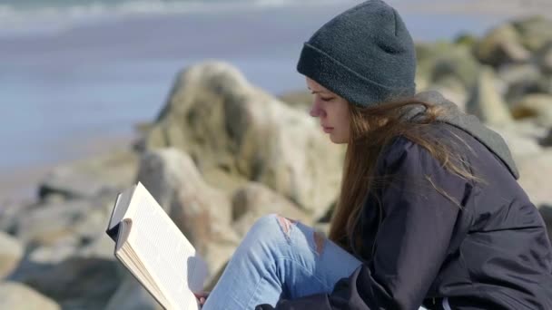 Fille lit un livre tout en étant assis au bord de l'eau — Video