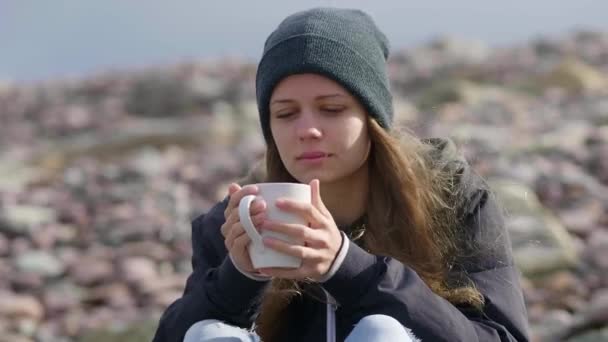 Hermosa chica con una taza de café sentado en el paseo marítimo — Vídeos de Stock