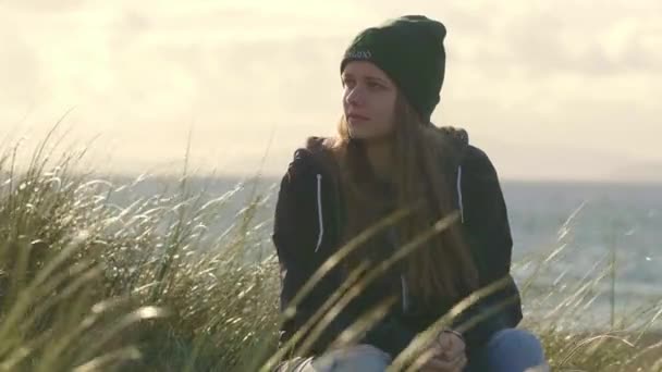 Girl sits in reed grass and loves the country of Ireland — Stock Video