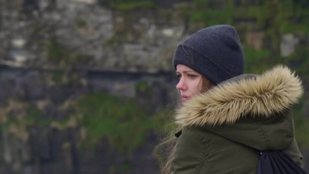 Nahaufnahme einer jungen Frau, die an den Klippen von Moher sitzt — Stockvideo