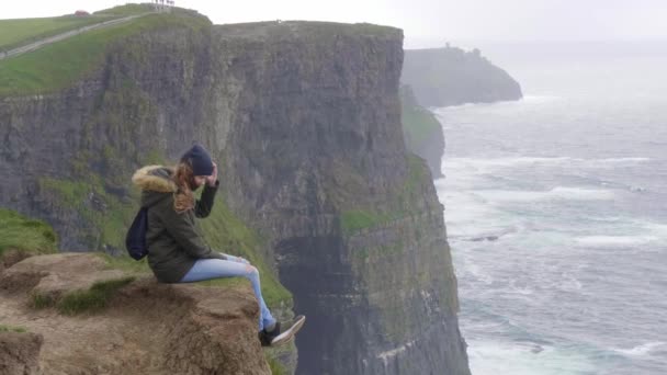 Красива дівчина виглядає над океаном на Кліф Могер — стокове відео