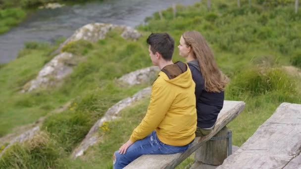 Dos amigos se sientan en un banco y disfrutan del increíble paisaje — Vídeos de Stock