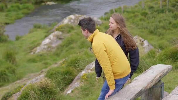 Twee vrienden doen een wandelpad door Ierland zitten op een bankje — Stockvideo