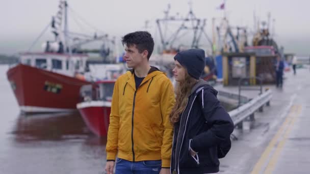 Pareja joven se para en el puerto de Dingle y observa los barcos — Vídeos de Stock