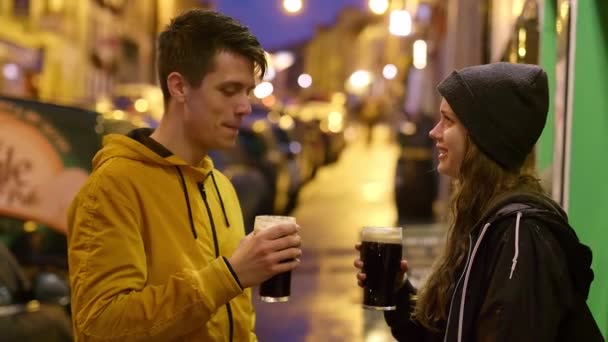 Dois amigos bebem um copo de cerveja escura à noite — Vídeo de Stock