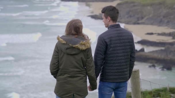 Pareja joven enamorada se encuentra en los escarpados acantilados de la costa oeste irlandesa — Vídeo de stock