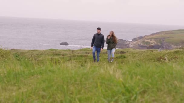 Dois amigos caminham pelos campos de grama na Irlanda — Vídeo de Stock