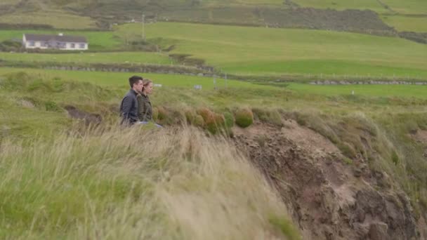 Dos amigos se sientan en los campos de hierba profunda de Irlanda y disfrutan de la gran naturaleza — Vídeo de stock